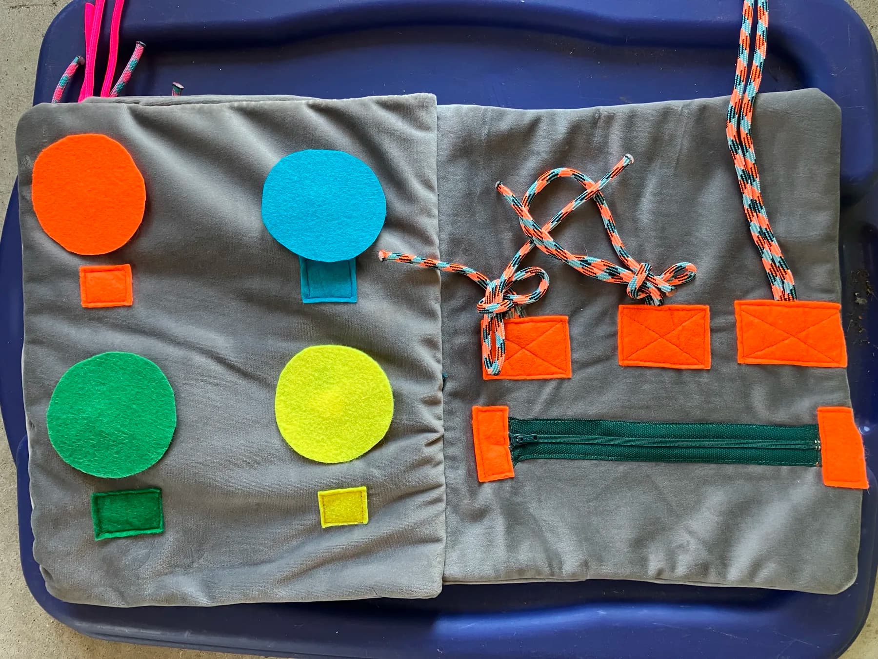 Open custom sensory book with felt shapes, a zipper and lacing cords.